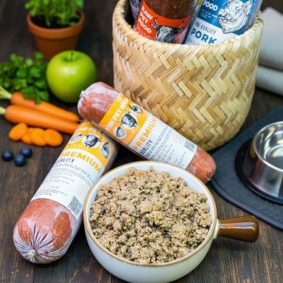 Thức Ăn Cho Chó Tươi Tốt Nhất dòng Premium với thịt bò xay nhuyễn kết hợp rau củ như cà rốt và rau xanh. Sản phẩm được đặt cạnh giỏ nguyên liệu và tô thức ăn đầy đặn, thể hiện sự tươi sạch và giàu dinh dưỡng.